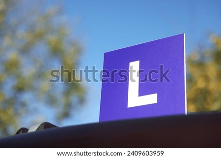 L-plate on car outdoors, space for text. Driving school