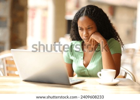 Serious black woman checking laptop in a bar terrace Royalty-Free Stock Photo #2409608233