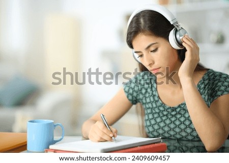 Student wearing headphone listening audio guide studying at home