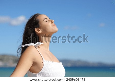 Profile of a relaxed woman in white dress breathing fresh air on the beach a summer sunny day