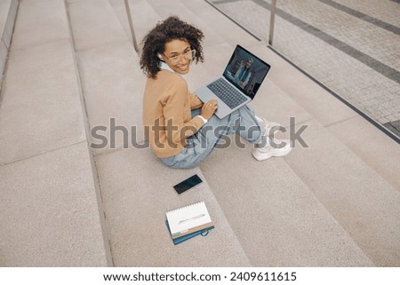 Female freelancer have a video conference with colleague sitting on stairs outside