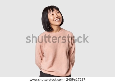 Young Chinese woman posing on studio background relaxed and happy laughing, neck stretched showing teeth.