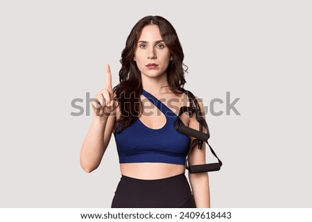 Young athlete with resistance band in studio showing number one with finger.