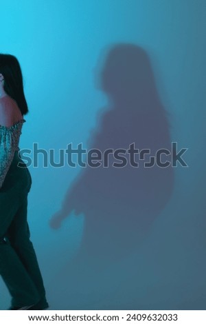 Vertical  photo art. Trendy blue color studio light on the wall. Shadow of a woman mooving out of sight.Conceptual