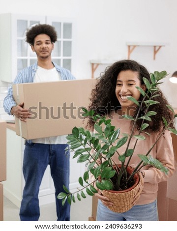 African American couple, man woman, collect clothes and plants in cardboard boxes for moving. happy young people relocating to new home. mortgage or rental of real estate. moving movers service Royalty-Free Stock Photo #2409636293