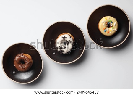 Donut in a 3 Chinese plate set isolated on white background a small fried cake of sweetened dough - chocolate - oreo - candy - Top view Royalty-Free Stock Photo #2409645439