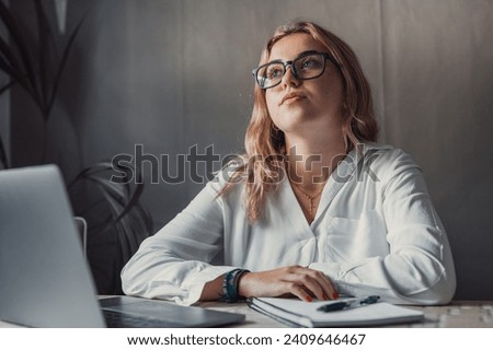 Young student girl sit at table with textbooks and laptop staring aside, studying alone in library, looks pensive and thoughtful search solution, prepare for exam, makes task feels confused or puzzled Royalty-Free Stock Photo #2409646467