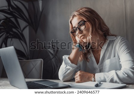 Discontented thoughtful woman with hand under chin bored at work, looking away sitting near laptop, demotivated office worker feels lack of inspiration, no motivation, boring routine, creative crisis Royalty-Free Stock Photo #2409646577