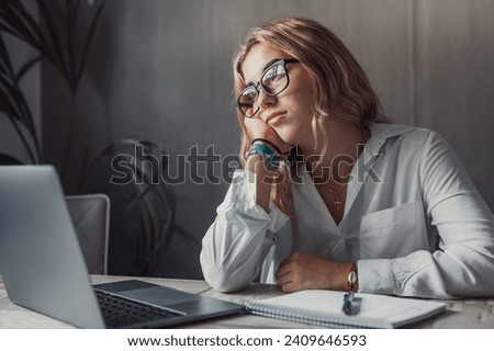 Discontented thoughtful woman with hand under chin bored at work, looking away sitting near laptop, demotivated office worker feels lack of inspiration, no motivation, boring routine, creative crisis Royalty-Free Stock Photo #2409646593