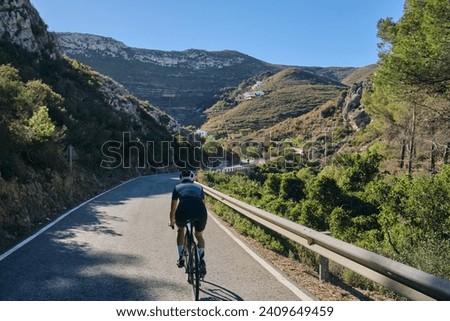 A woman cyclist riding on mountain road. Cyclist on the windy road in mountains. Costa Blanca, Alicante, Spain Royalty-Free Stock Photo #2409649459