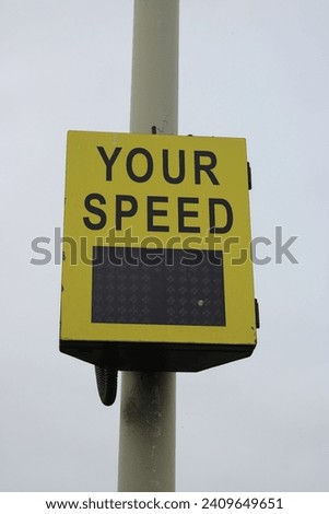 Yellow vehicle activated speed sign showing speed to driver, sign black attached to a lamp post
