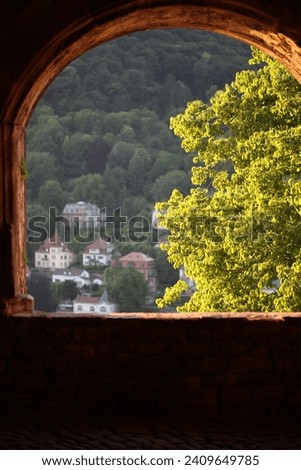 Ancient arch windows in a castle with scenic hills - Contrasting view from inside ancient Castle at vivid Heidelberg, Germany - View of old town from inside the castle