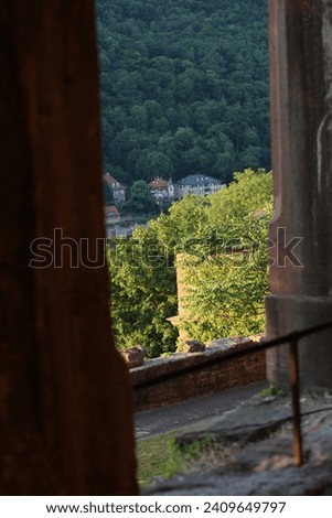 Ancient arch windows in a castle with scenic hills - Contrasting view from inside ancient Castle at vivid Heidelberg, Germany - View of old town from inside the castle