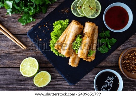 Spring rolls and sauces on wooden table Royalty-Free Stock Photo #2409651799
