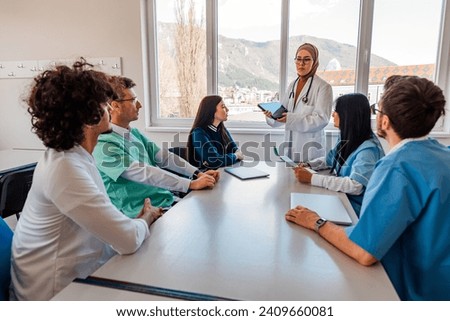 A medical team of doctors discussing and planning a work strategy at a meeting in the conference room using modern technology, diverse multicultural business people working together..