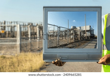 Elderly man holding old tv frame outdoors. Wind turbine power station on television. Renewable energy power plant