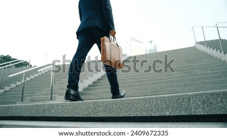 Top view of smart business man walking up stairs with bag in the hand. Professional project manager climb up the stair and going to workplace. Increasing skill, getting promotion, traveling. Exultant. Royalty-Free Stock Photo #2409672335