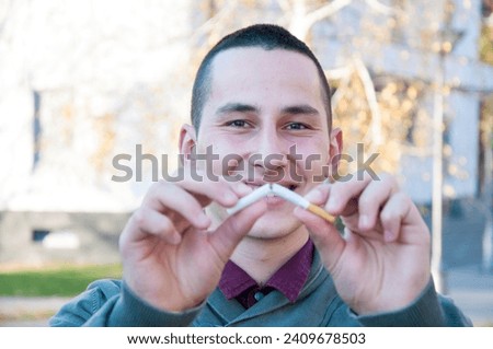 Handsome young happy man with broken cigarette. No more garbage in my lungs. Stop smoking concept.