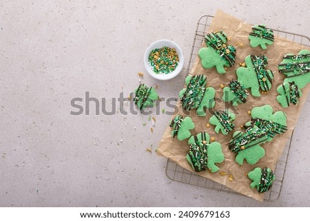 Shamrock cookies for Saint Patricks day with chocolate glaze and sprinkles, green clover leaf cookies on parchment paper