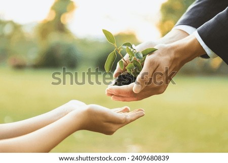 Businessman handing plant or sprout to young boy as eco company committed to corporate social responsible, reduce CO2 emission and embrace ESG principle for sustainable future.Gyre Royalty-Free Stock Photo #2409680839