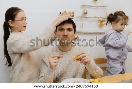 A girl puts a crown on an adult guy who ate a royal galette.