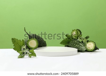 A podium with fresh bitter melon on a green background. Bitter melon is rich in vitamins and proteins, not only beneficial for health but also an ingredient that helps the body detoxify very well. Royalty-Free Stock Photo #2409705889