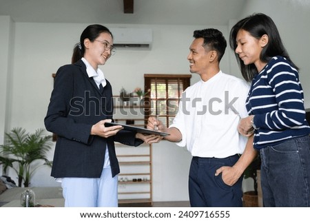 Young happy smiling couple read agreement with realtor and looking through the contract of real estate sale going to signing a deal