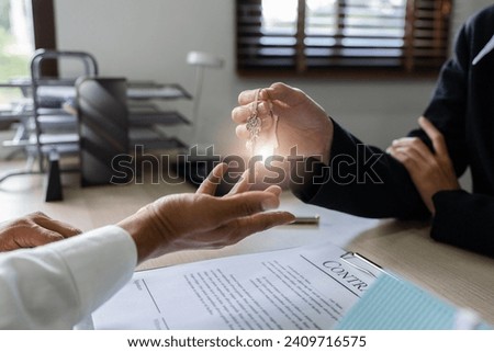 Real estate agent give the customer the keys after signing contract success with Home Loan and Home Insurance in the Office