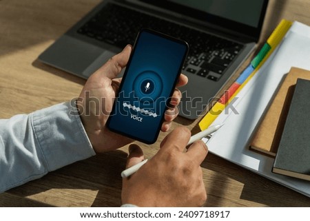 A voice recording man holding his smartphone screen generates AI technology for language and communication in a mobile application. Record sound