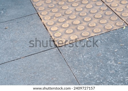 bright yellow tiles called tactile tiles or guiding blocks which are useful as walking guides for disabled pedestrians especially the blind