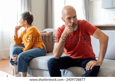 Senior spouses feeling offended and upset after an argument at home, elderly husband and wife suffering emotional challenges and conflict resolution in relationships, sitting on couch in living room Royalty-Free Stock Photo #2409738877