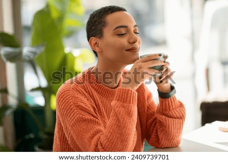 Glad calm pretty young latin woman enjoy peace and spare time, drink cup of coffee, warm moment in modern cafe, office interior. Rest, relax, ad and offer, human emotions, lifestyle Royalty-Free Stock Photo #2409739701