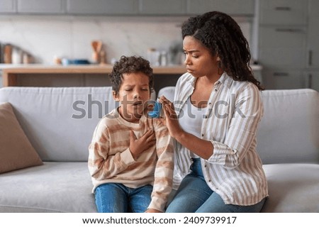 Preventing Attack. Caring mother giving blue asthma inhaler to her sick son at home, loving young mom taking care about ill preteen male kid suffering breathing problem, closeup shot Royalty-Free Stock Photo #2409739917