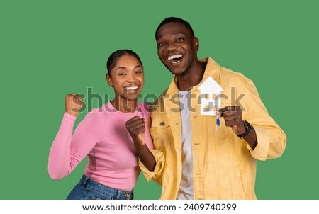 Photo of cheerful nice good cool beautiful lovely millennial black couple having just purchased new accommodation while isolated on green background, showing key and paper house