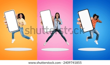 Three Excited People Jumping With Big Blank Smartphone In Hands On Platforms Against Colorful Backgrounds, Happy Multiethnic Man And Women Pointing At White Screen, Recommending New App, Mockup