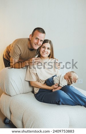 A young family with a newborn baby. Happy mother and father kissing their child. Parents and a smiling child in their arms