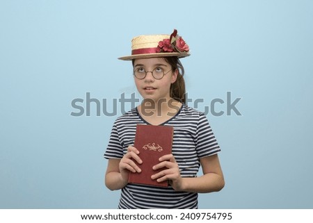 Read novel. A girl in a retro fashion of yesteryear, a straw hat with flowers, glasses and a book in her hand.