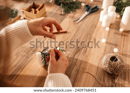 Close-up of a young woman's hands decorating candles for Christmas or New Year. Decorating items for the holiday and making gifts.