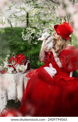 girl in a red dress with a white rabbit in the spring garden.