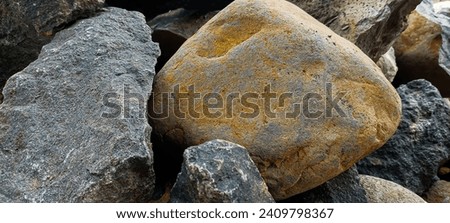 Large chunks of gray and orange natural stone as the basic material for a building Royalty-Free Stock Photo #2409798367
