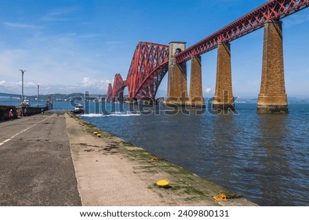 The Forth Bridge on Firth of Forth estuary from South Queensferry boat ramp pier in Scotland, UK. Royalty-Free Stock Photo #2409800131