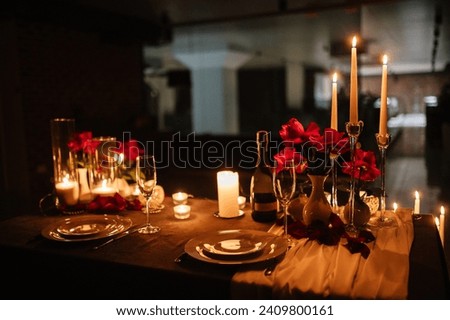 Romantic dinner setup at night. Champagne glasses, flowers. Table setting for a couple, Valentine's Day evening, burning candles for a surprise marriage proposal. Candle light date in a restaurant. Royalty-Free Stock Photo #2409800161
