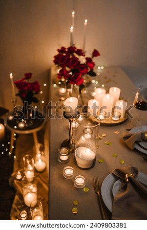 Romantic dinner setup at night. Wine glasses, flowers. Table setting for couple, Valentine's Day evening, burning candles for surprise marriage proposal. Candle light date in restaurant. Top view Royalty-Free Stock Photo #2409803381