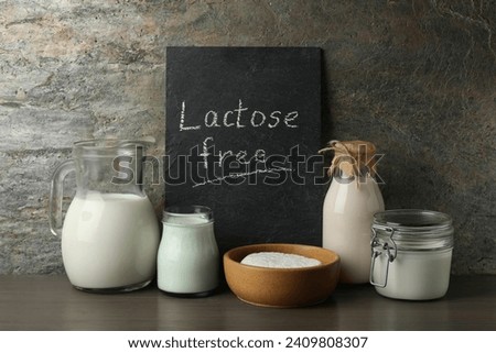 Dairy products and board with phrase Lactose Free on wooden table near grey wall Royalty-Free Stock Photo #2409808307