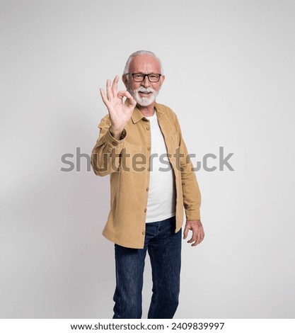 Portrait of happy senior male marketing manager showing OK sign against isolated white background