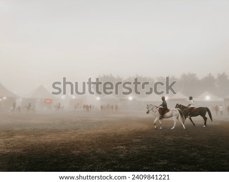 2 horses walking together prior to race start with fog climate.  Royalty-Free Stock Photo #2409841221
