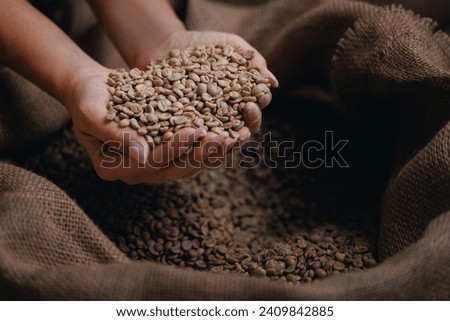 Professional worker hold green coffee beans shaped heart on background jute bag in warehouse. Concept roaster factory, love with espresso. Royalty-Free Stock Photo #2409842885