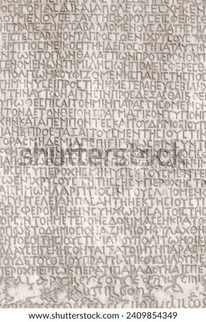 Retro text background. Fragment of ancient inscription (imperial law in ancient Greek language), carved on marble block. Monochrome. Ancient Miletus, Turkey (Turkiye). Ancient art and history concept