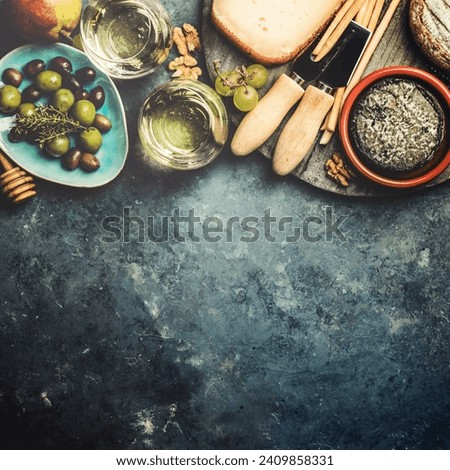Glasses of white sparkling wine with cheese, grapes, nuts , olives and honey on blue concrete background