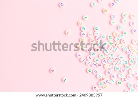 Beads with letters scattered on a pink background. Place for text.
